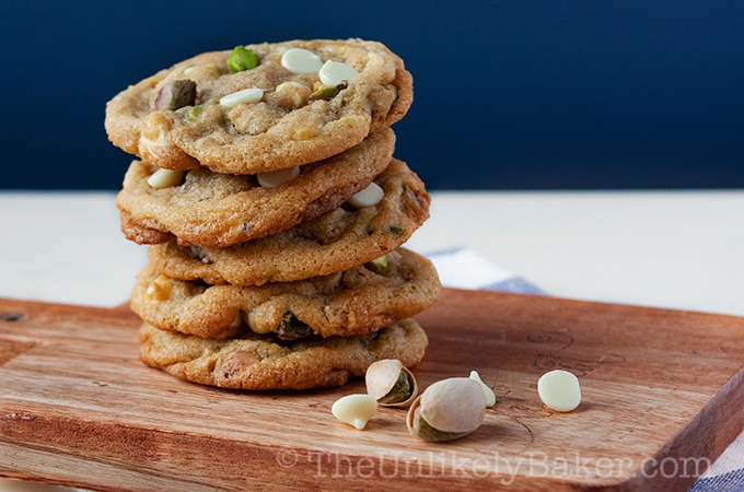 A stack of Pistachio White Chocolate Chip Cookies on a board.