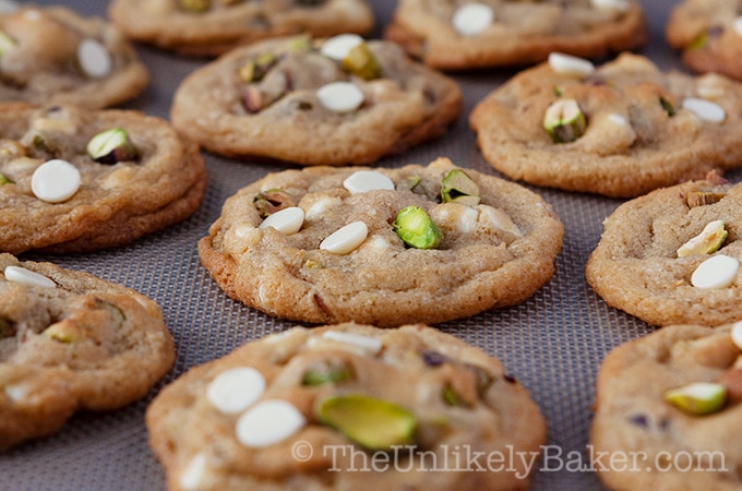 Freshly baked white chocolate pistachio cookies on a silicone mat.