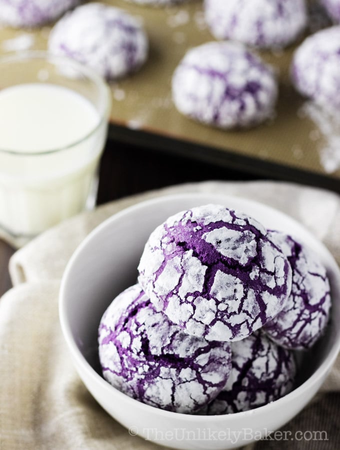 Ube crinkles in a bowl with a glass of milk in the background.