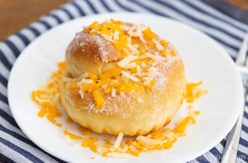 Freshly baked cheese ensaymada bread on a white plate