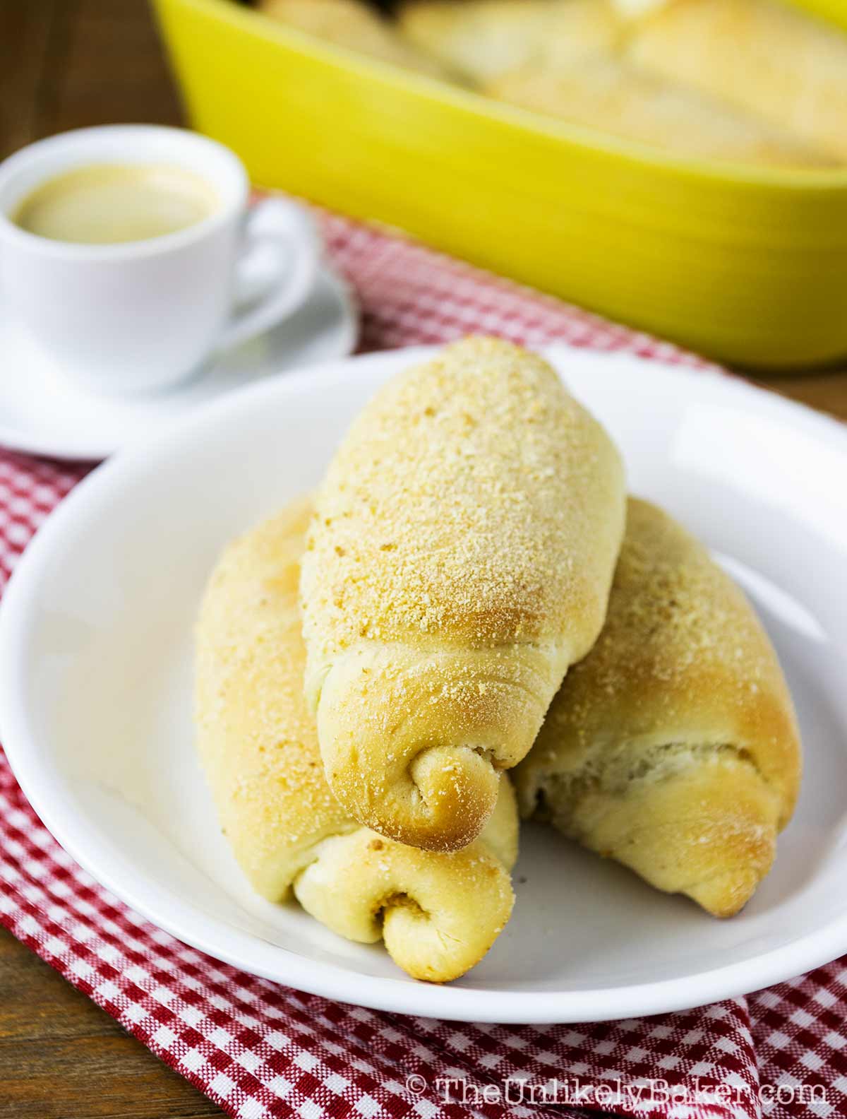 Spanish bread on a plate beside a cup of coffee.