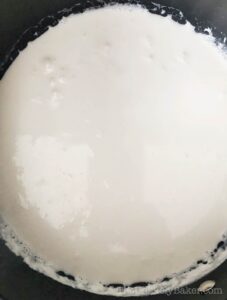 Simmering coconut milk in a saucepan.
