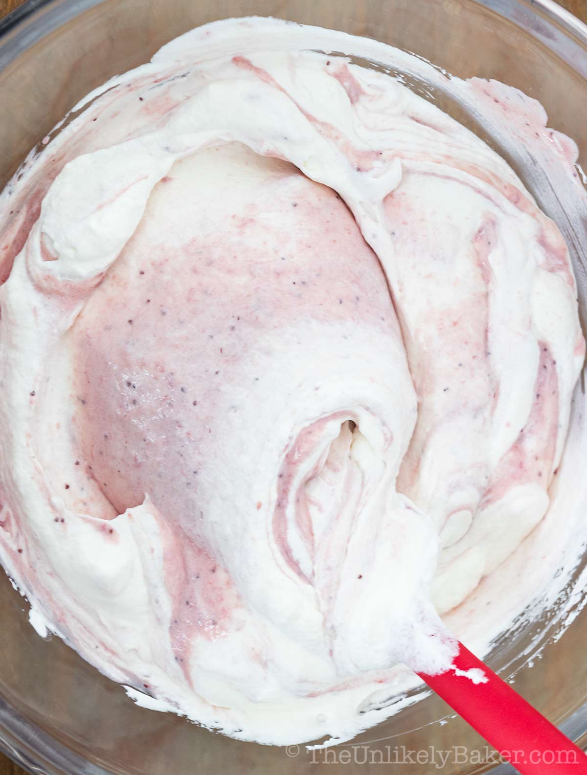 Whipped cream being folded into strawberry mixture.