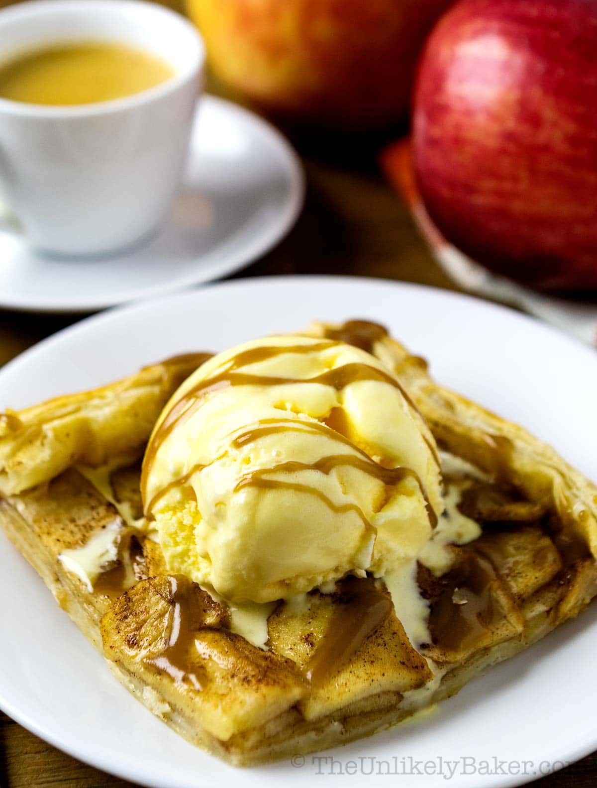 Slice of puff pastry apple galette with ice cream and caramel sauce.