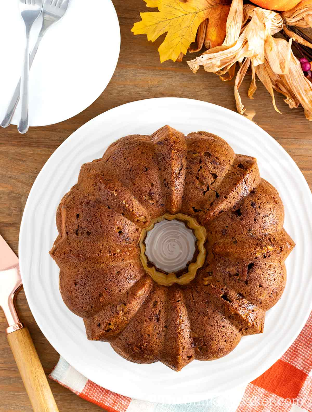 Pumpkin bundt cake with cream cheese filling on a cake platter.