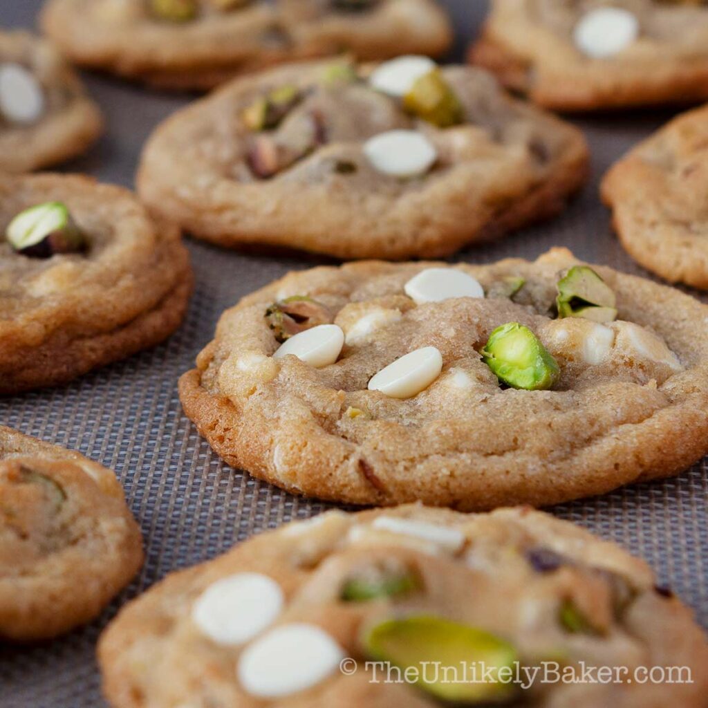 Freshly baked pistachio white chocolate cookies on a tray.