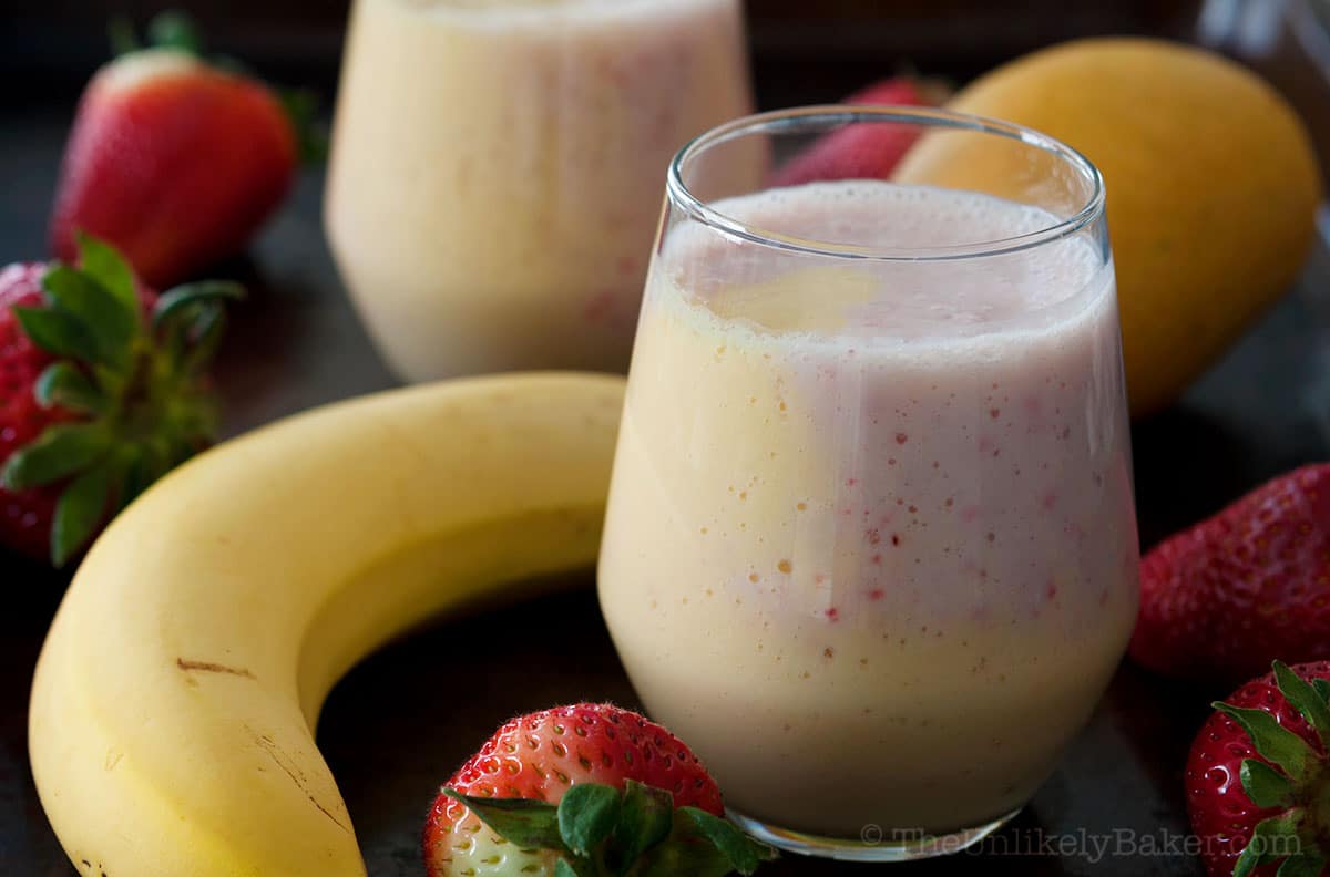 Layered mango banana strawberry smoothie in a glass.