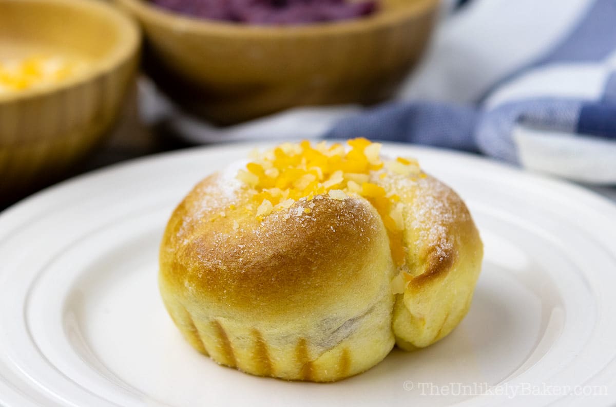 Freshly baked ensaymada with ube filling on a plate.