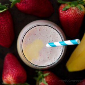 Overhead shot of strawberry mango banana smoothie in a glass.