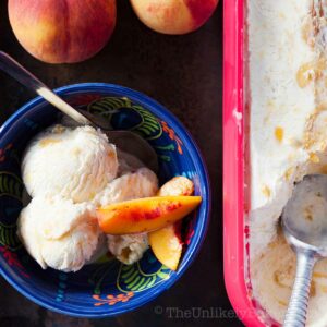 No churn peach ice cream with fresh peach slices in a bowl.