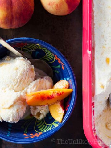 No churn peach ice cream with fresh peach slices in a bowl.