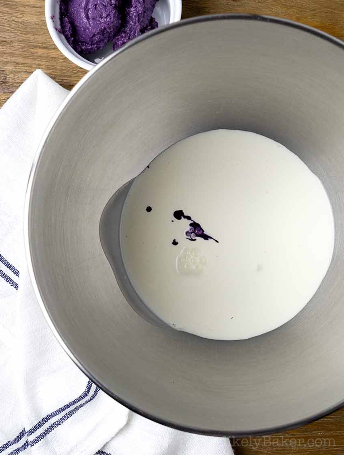 Heavy cream and ube extract in a bowl.