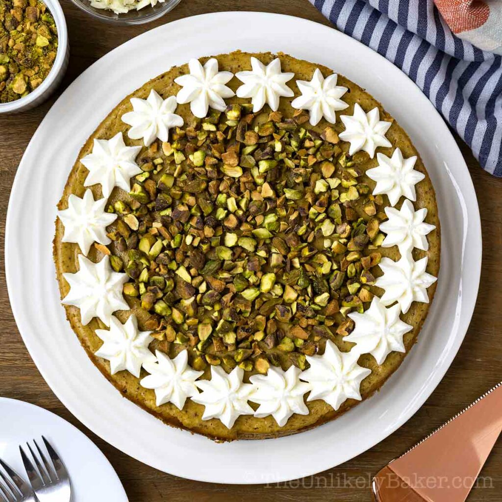Overhead shot of pistachio cheesecake with whipped cream and chopped pistachios.