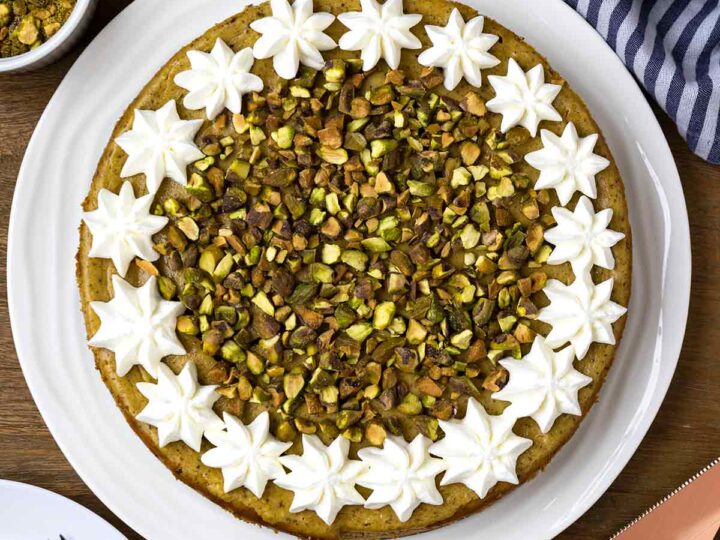 Overhead shot of pistachio cheesecake with whipped cream and chopped pistachios.