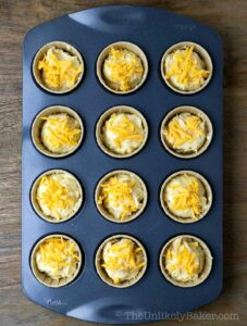 Cupcake batter sprinkled with cheddar cheese.