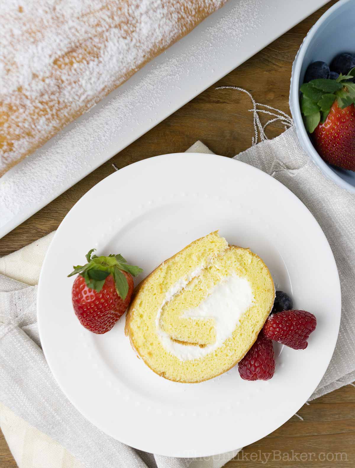 Slice of vanilla roll cake with whipped cream filling.
