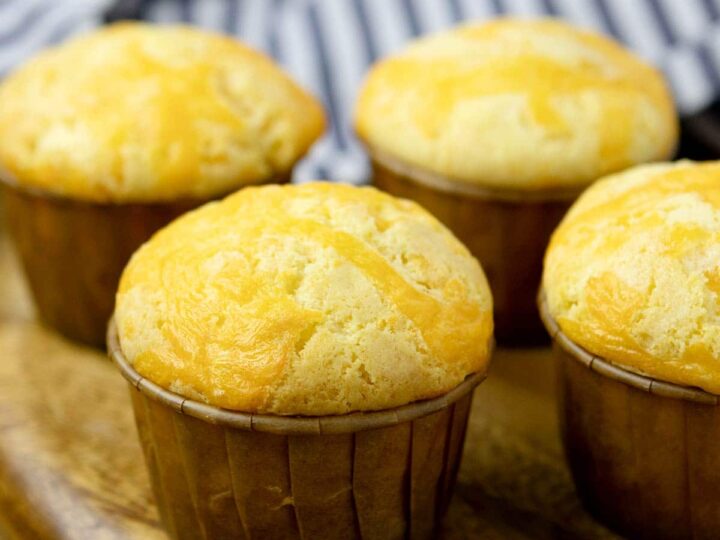 A group of cheese cupcakes on a wooden board.