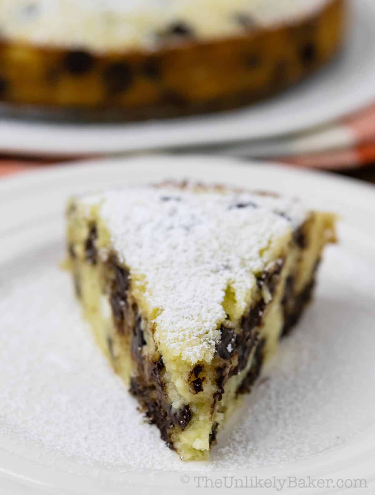 A slice of chocolate chip ricotta cake dusted with powdered sugar.