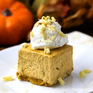 A piece of no bake pumpkin cheesecake bar with whipped cream topping.