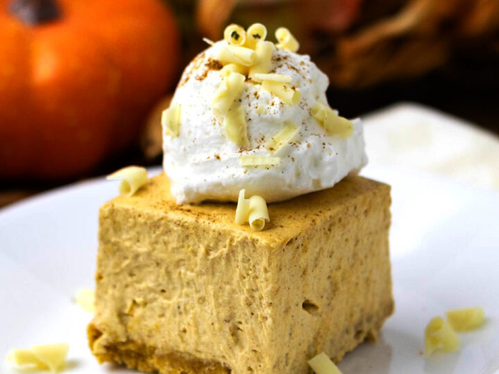 A piece of no bake pumpkin cheesecake bar with whipped cream topping.