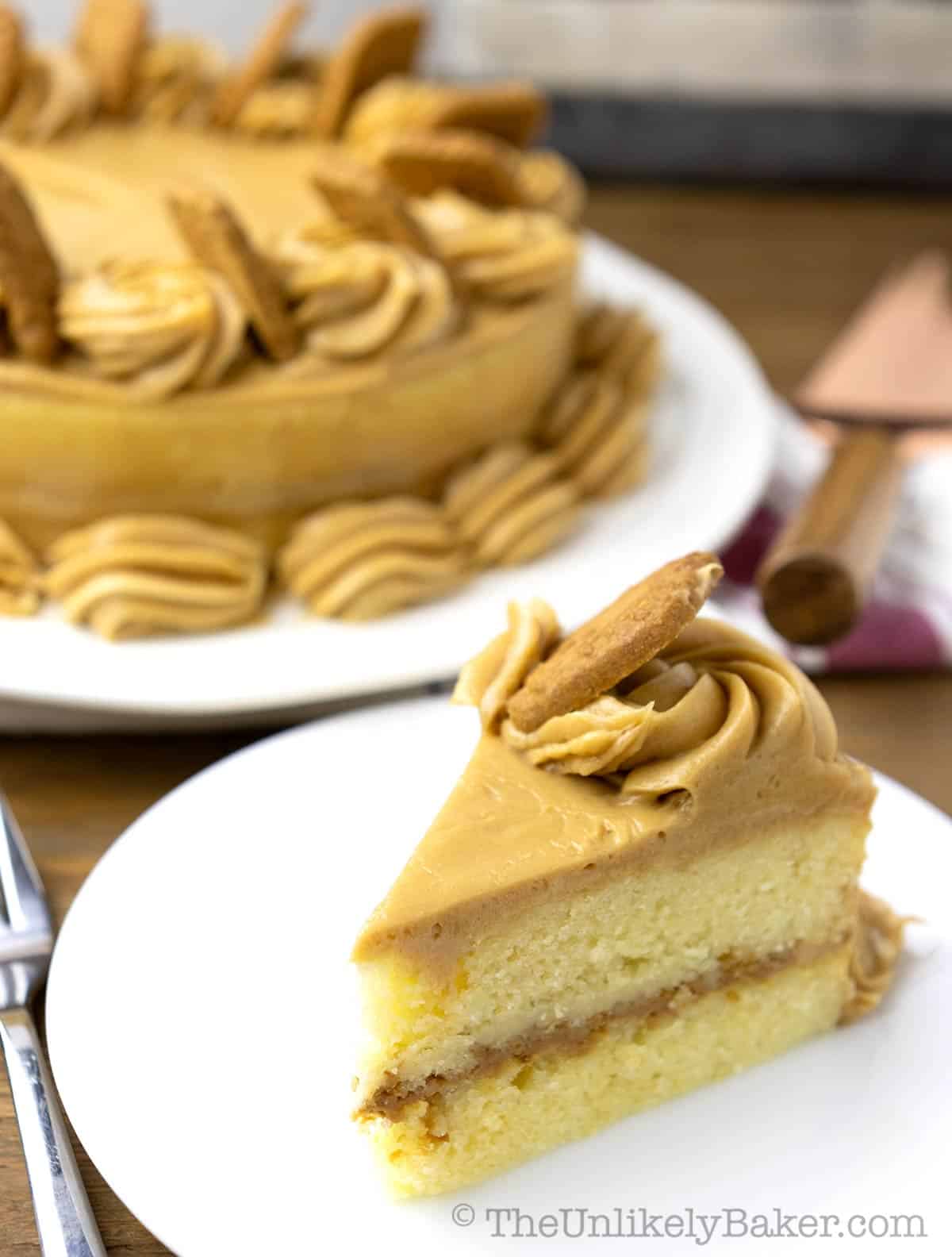A slice of vanilla layer cake with Biscoff frosting on a plate.