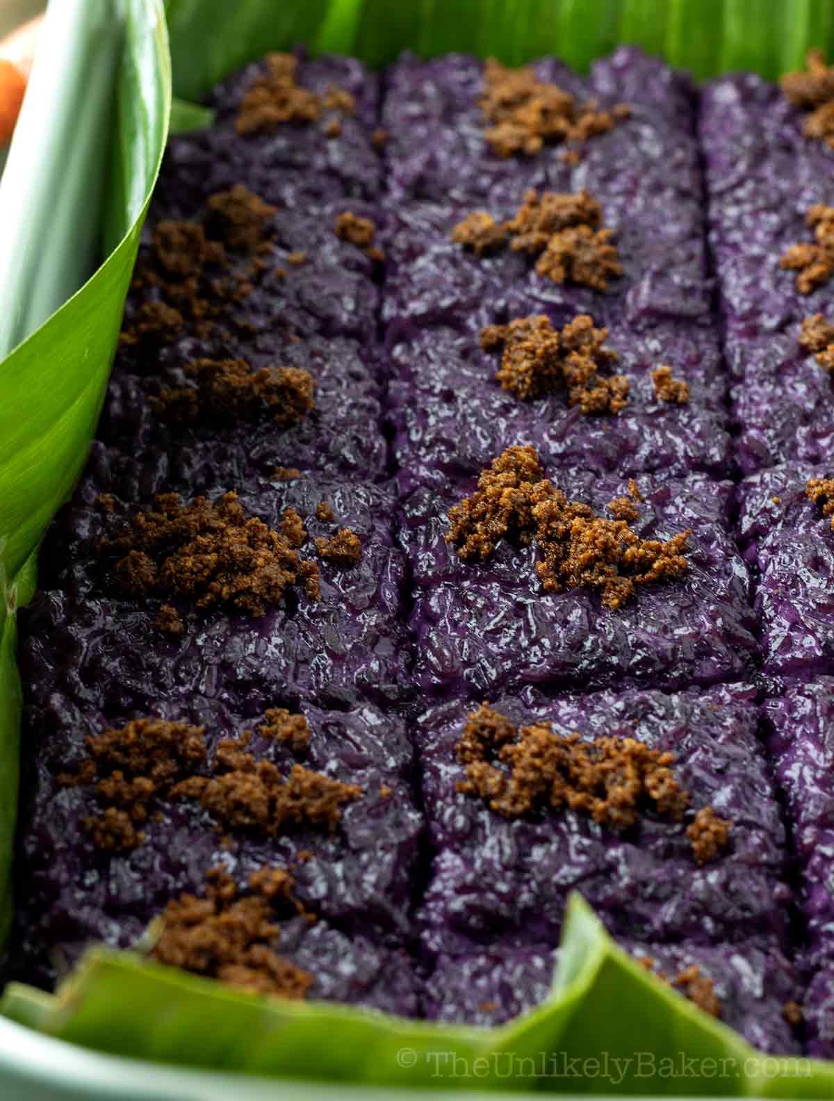 Filipino ube biko with latik in a baking dish lined with banana leaves.