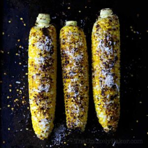 Three pieces grilled corn on the cob with chili butter and lime.