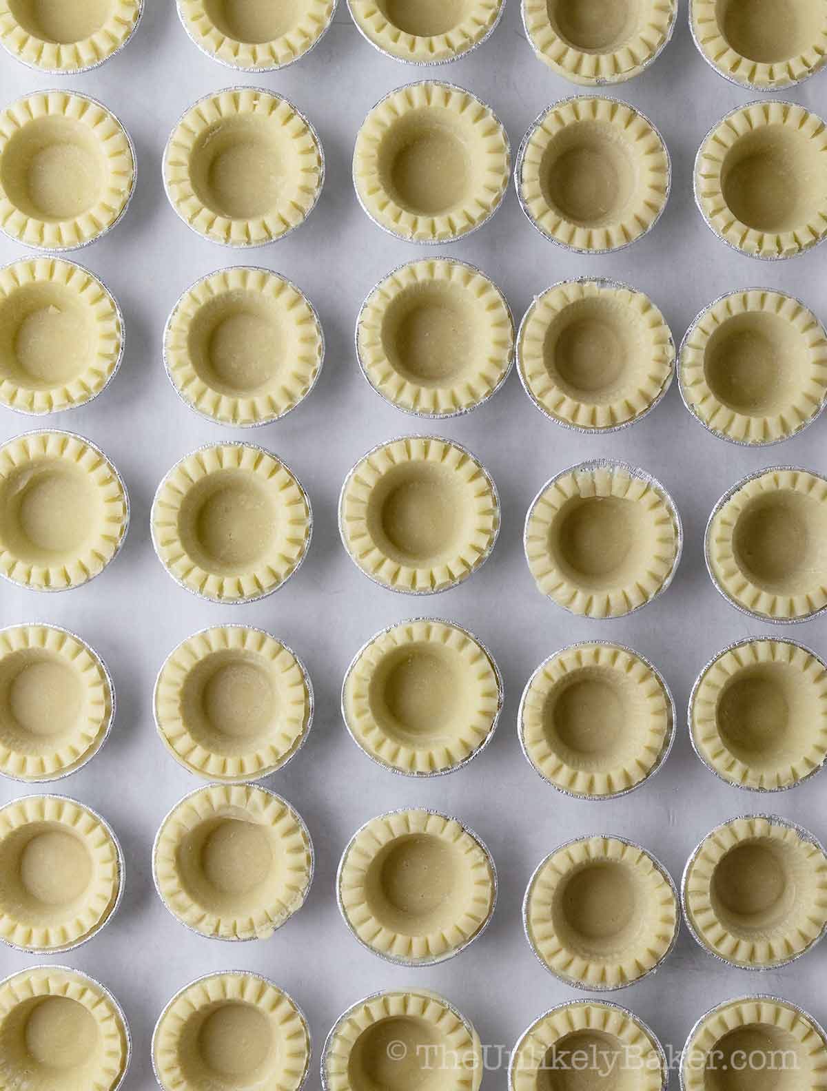 Frozen mini tart shells on a baking sheet.