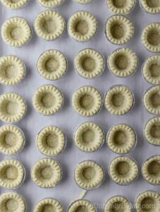 Baked tart shells on a baking sheet.