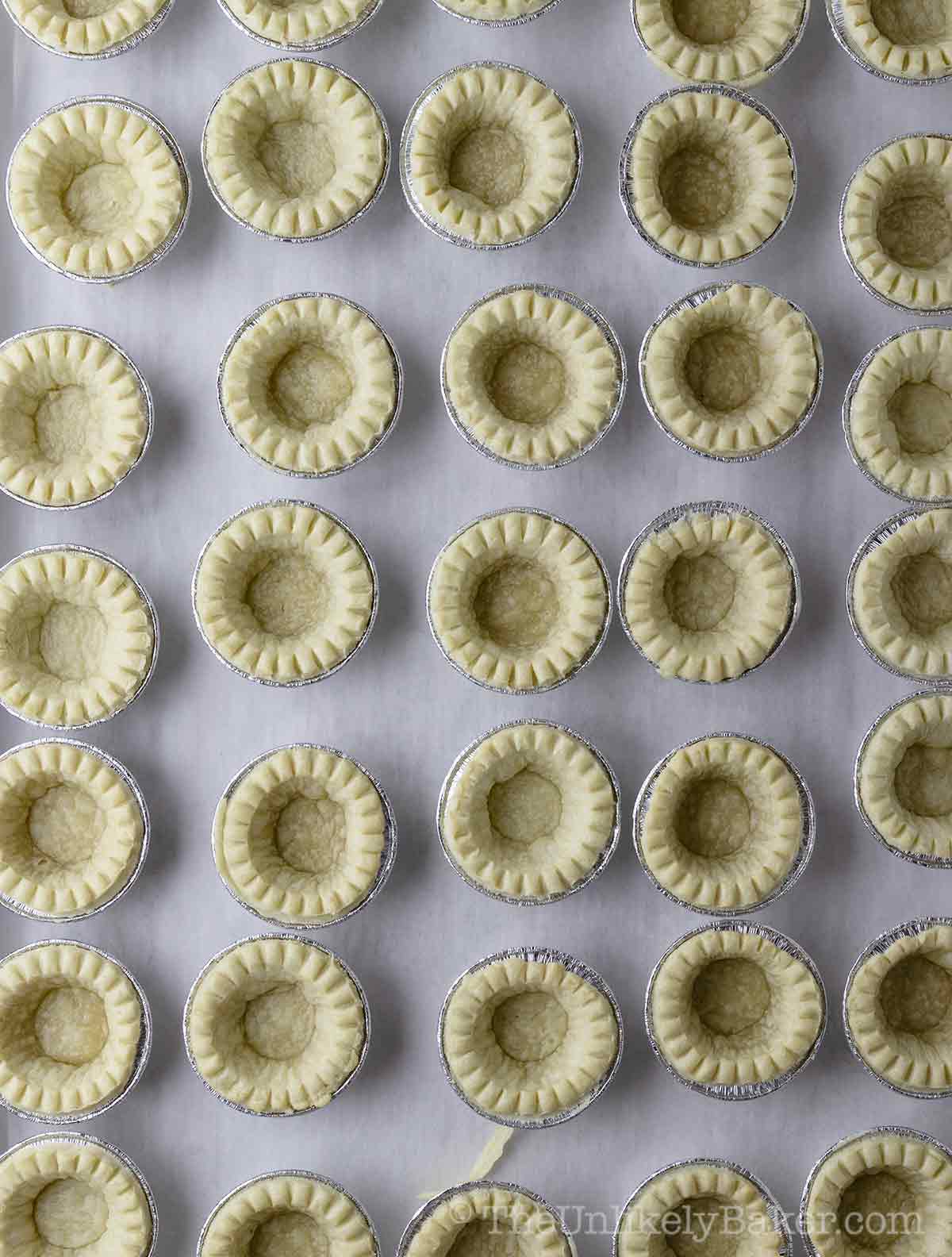 Baked tart shells on a baking sheet.