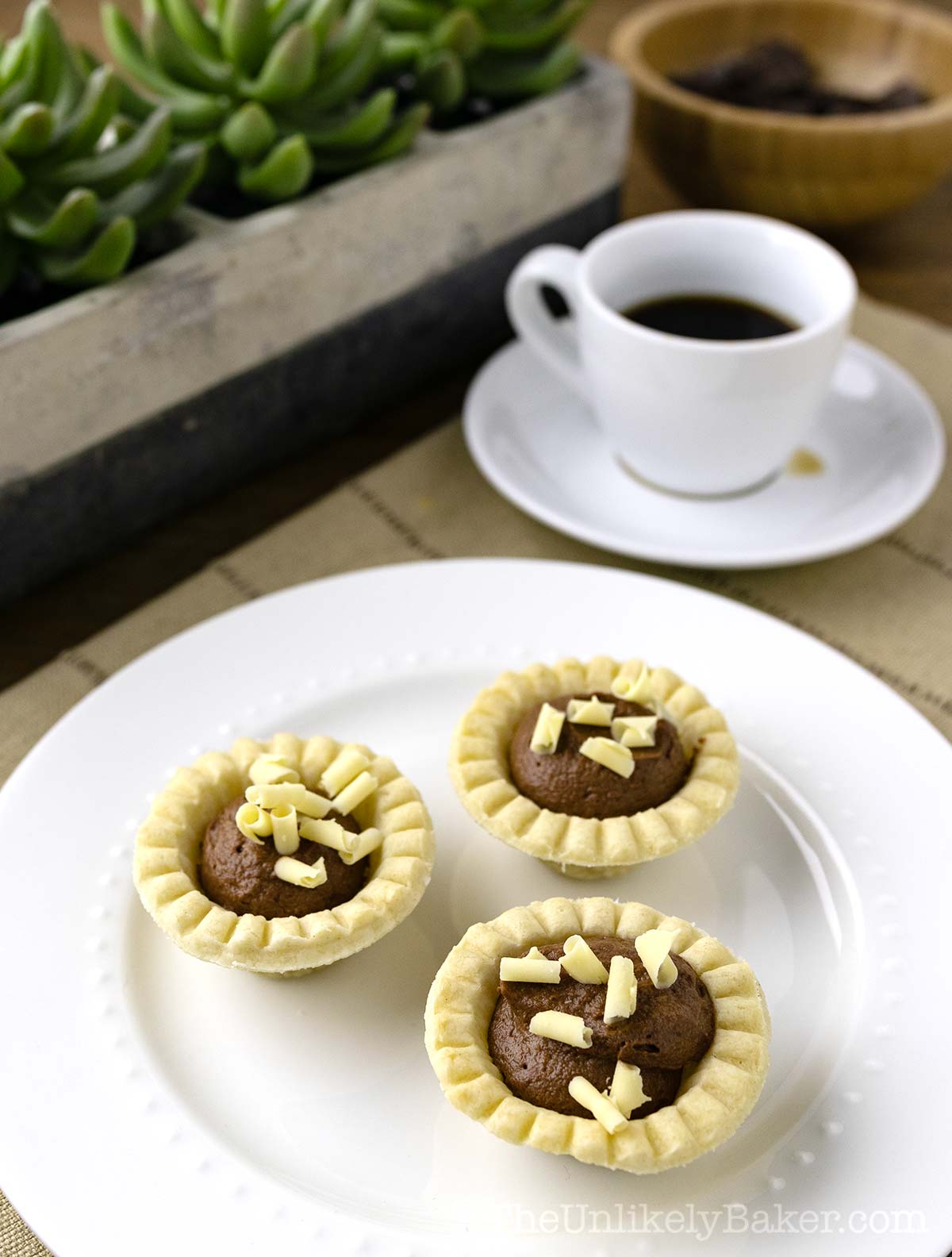 Mini chocolate tarts on a plate.