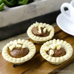 Mini chocolate tarts with shaved white chocolate on top.