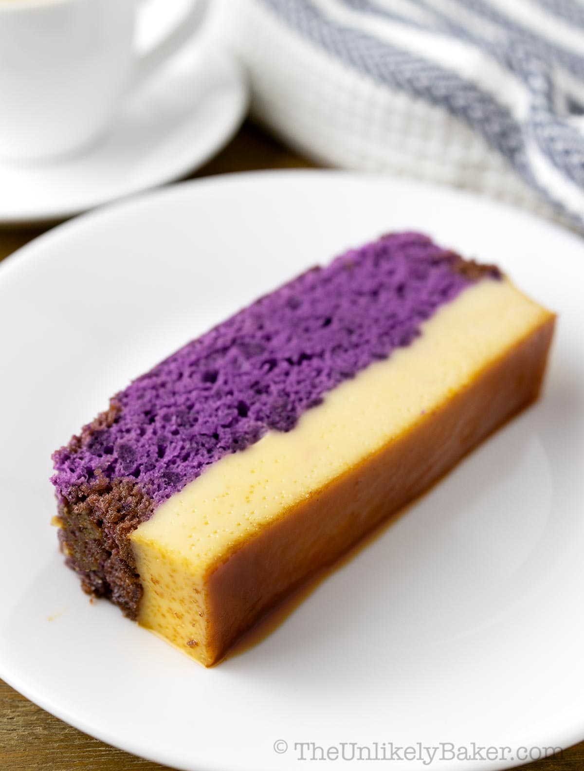 A slice of ube cake flan with coffee in the background.