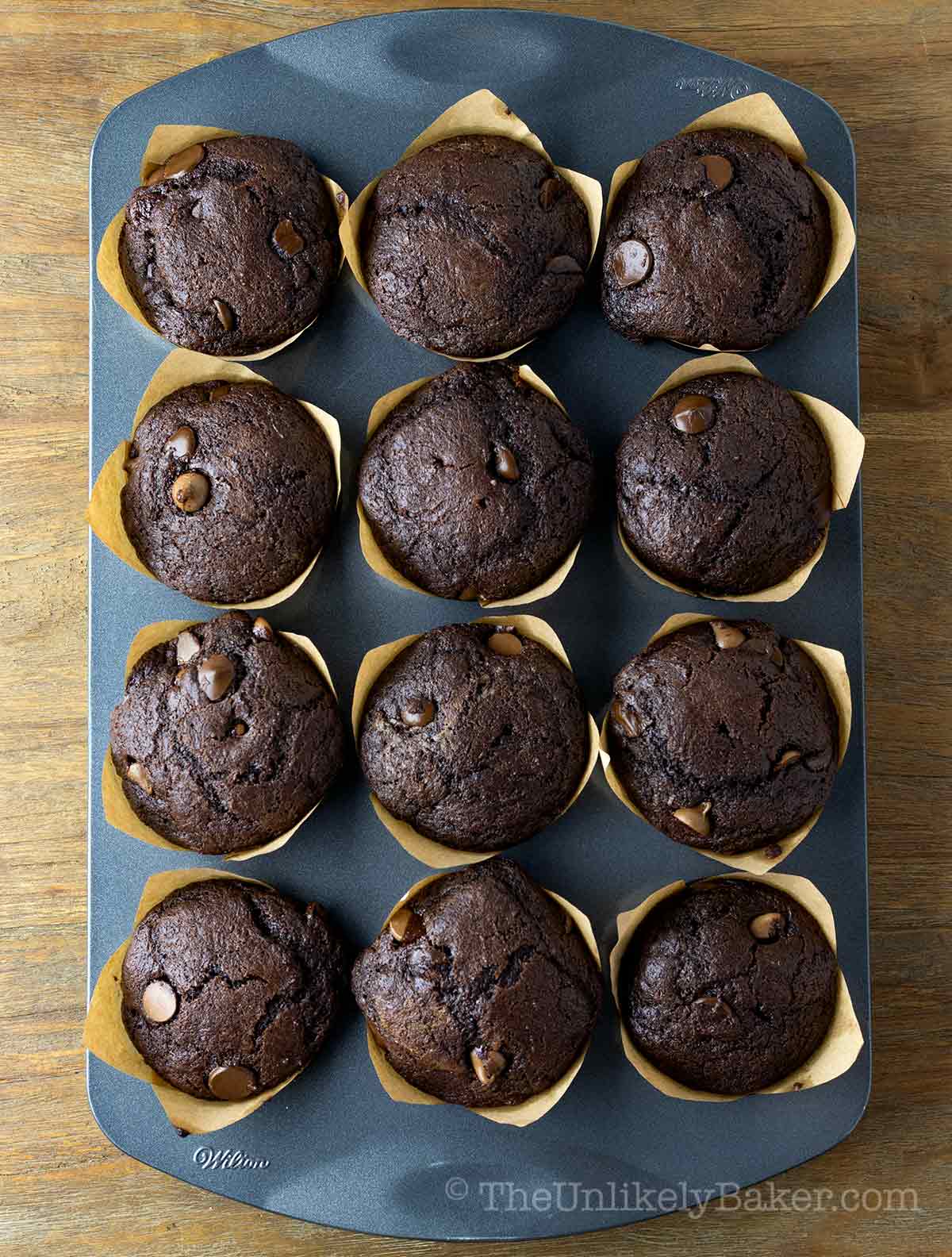 Freshly baked triple chocolate muffins in a pan.