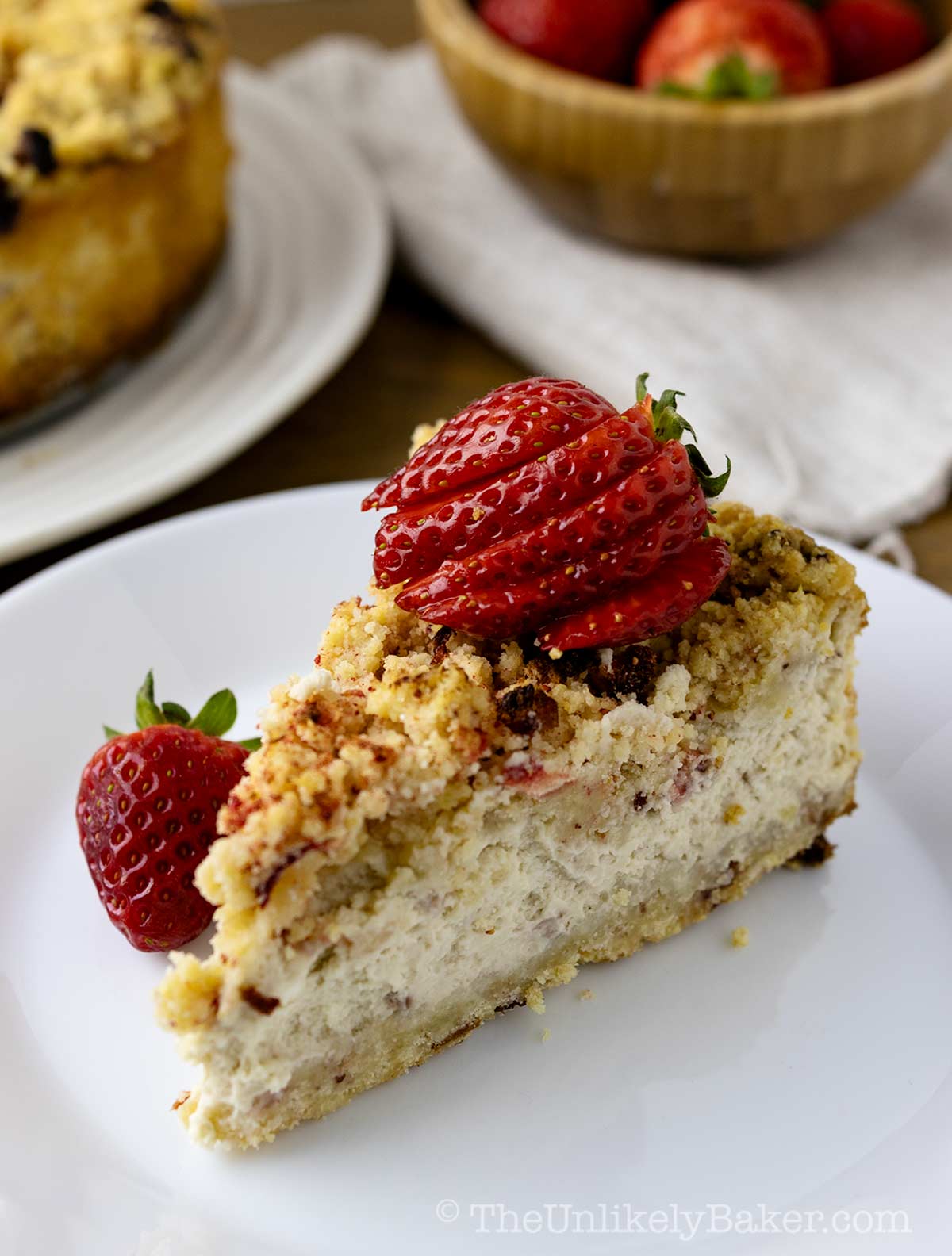 A slice of baked strawberry crunch cheesecake on a plate.
