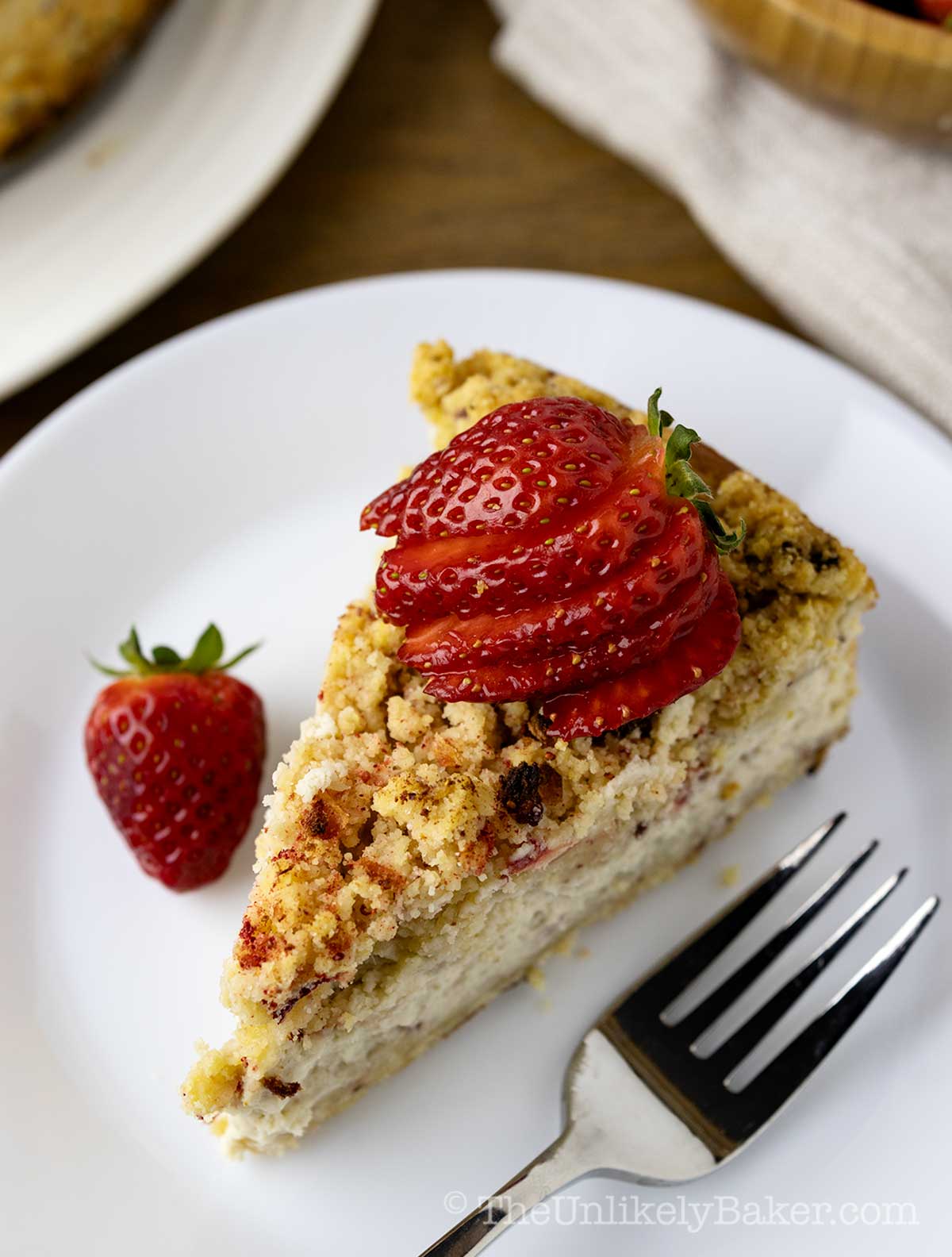 A slice of strawberry cheesecake topped with strawberry crunch crumble.