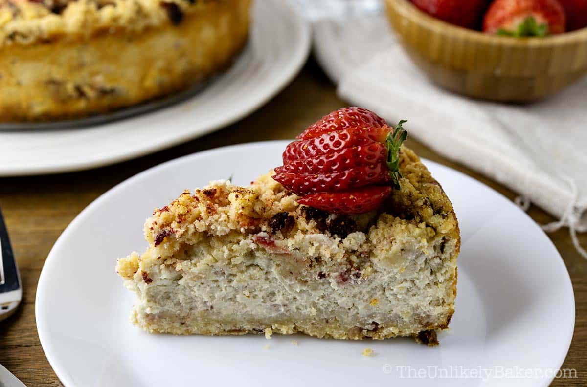 A slice of strawberry cheesecake crunch cake on a plate.