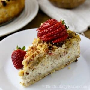 A slice of strawberry crunch cheesecake with fresh strawberries on top.