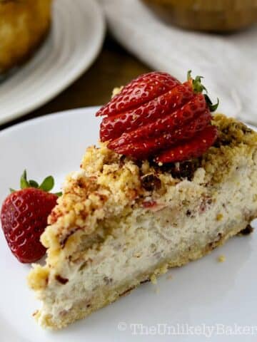 A slice of strawberry crunch cheesecake with fresh strawberries on top.