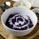 A bowl of ube champorado drizzled with milk.