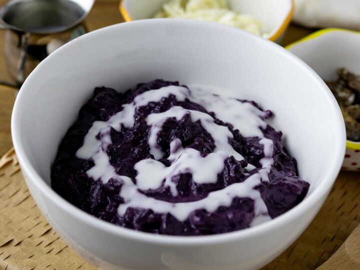 A bowl of ube champorado drizzled with milk.