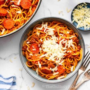 A bowl of Filipino style spaghetti with shredded cheese on top.