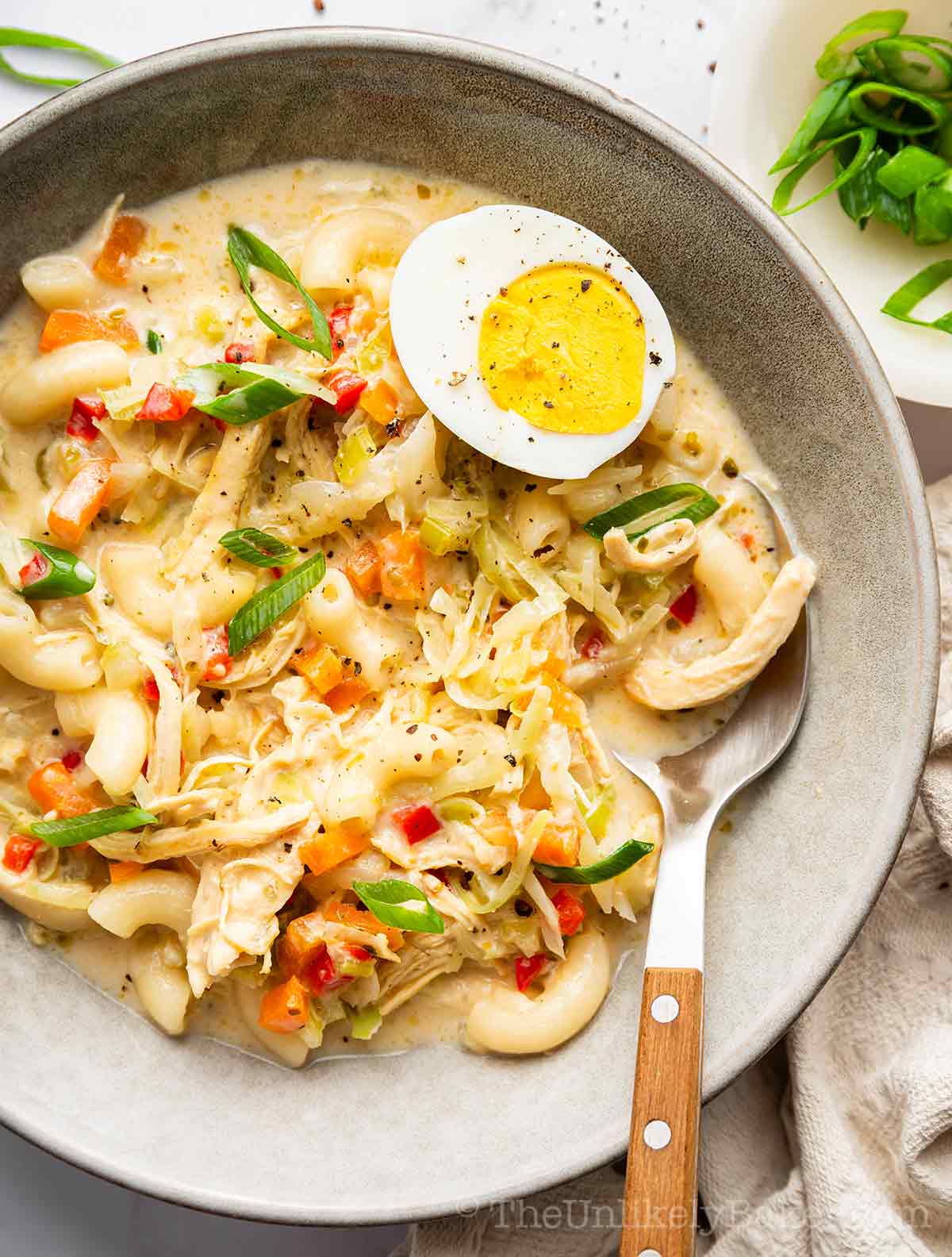 A bowl of macaroni sopas with a boiled egg.