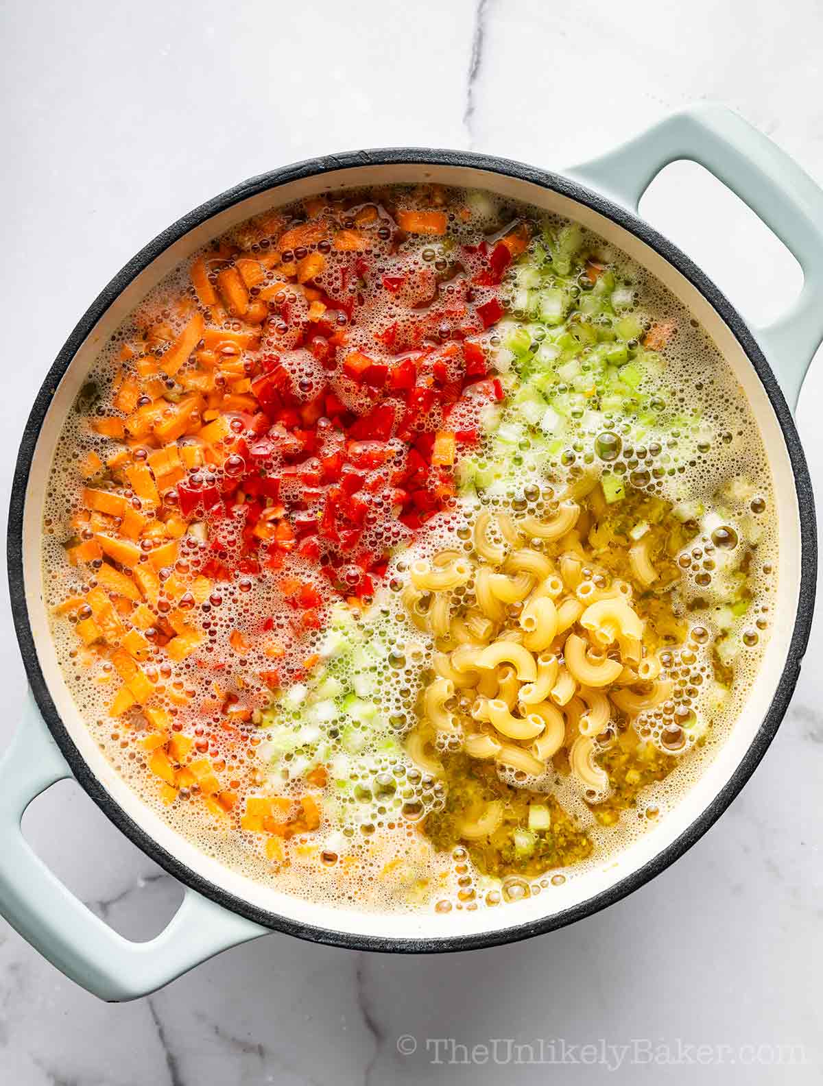 Vegetables and elbow macaroni added to broth.