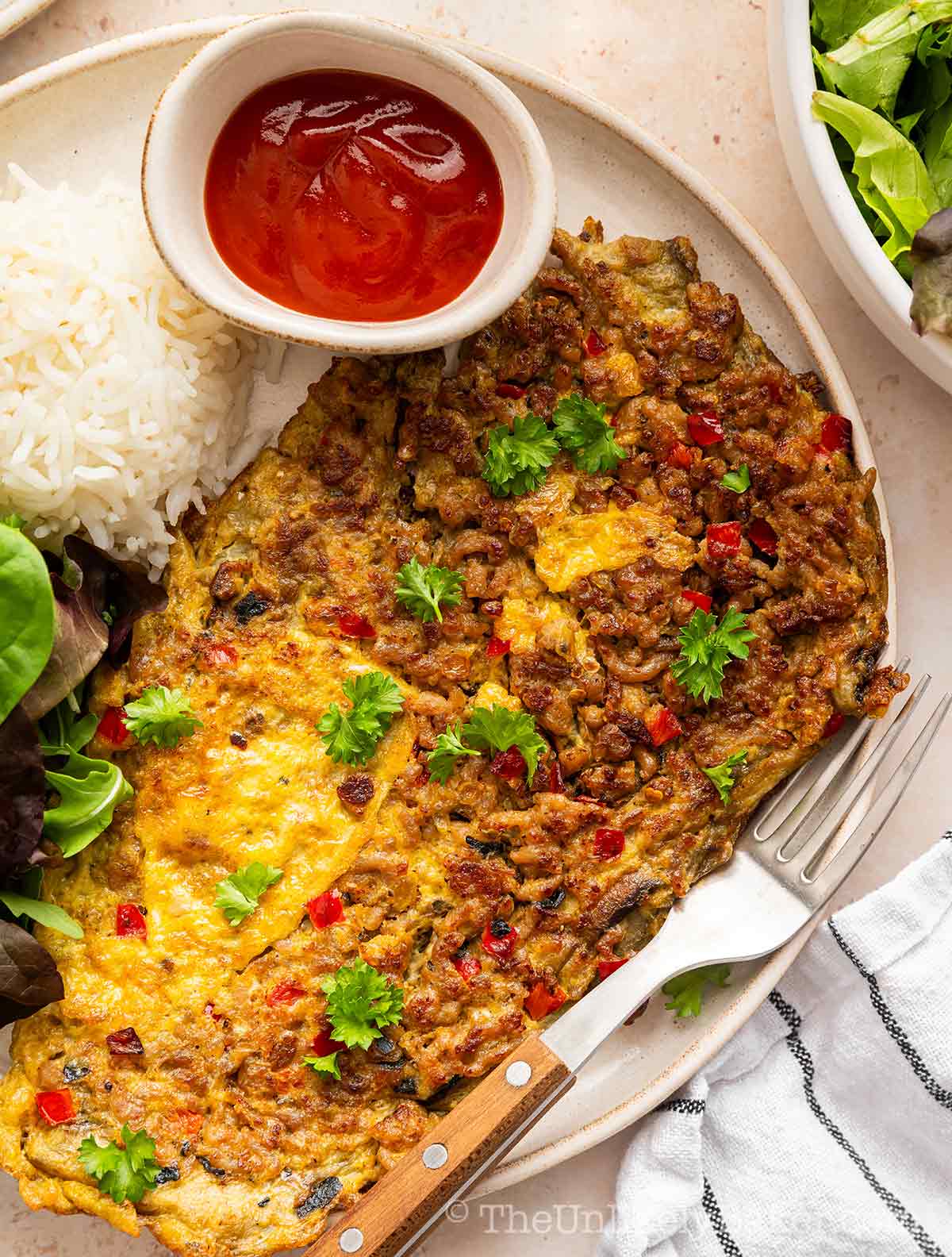 Filipino talong omelette on a plate with rice.