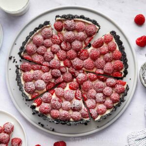White chocolate raspberry tart sprinkled with icing sugar.
