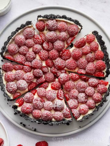 White chocolate raspberry tart sprinkled with icing sugar.