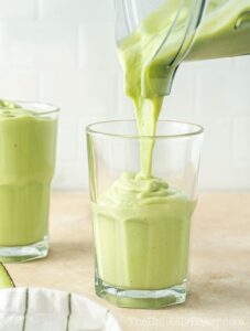 Avocado milkshake being transferred to cups.