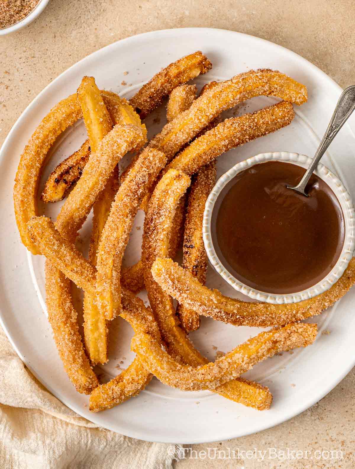 Crispy churros and silky chocolate sauce on a plate.